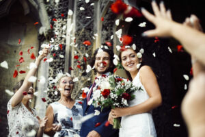 family throwing rose petals at the newly wed